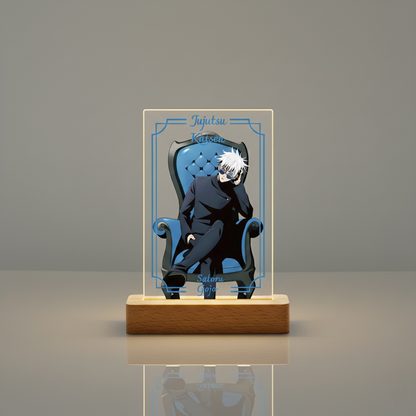 Satoru Gojo LED night lamp featuring a stylized illustration of the Jujutsu Kaisen character sitting on a throne, with an electric blue light glowing from the rectangular acrylic panel and a warm light from the wooden base.