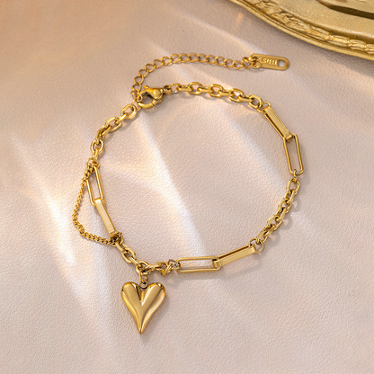 Amora anti-tarnish gold heart charm bracelet displayed on shimmering champagne silk