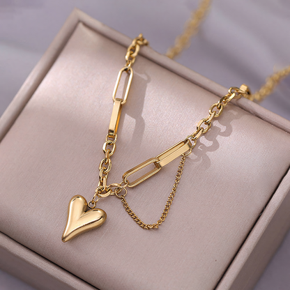 Detailed view of Amora gold heart charm and delicate draped side chain on soft beige leather box