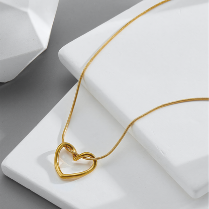 Elara gold plated anti-tarnish heart necklace resting on white geometric stone platforms