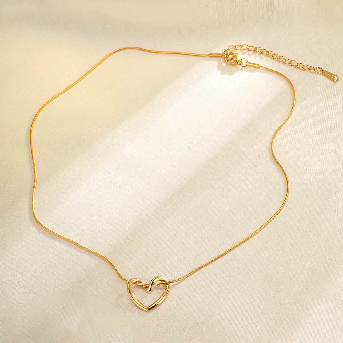 Full length view of Elara gold anti-tarnish heart necklace showing the delicate snake chain and adjustable clasp on silk