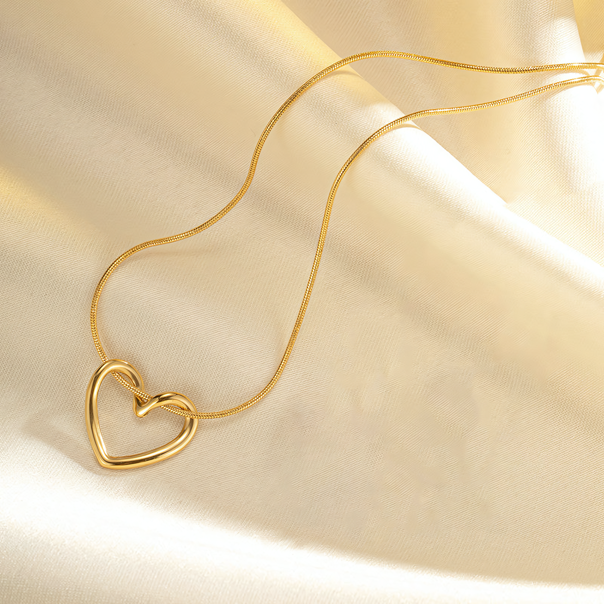 Close up of the modern open wire heart pendant sliding on the Elara gold anti-tarnish necklace chain