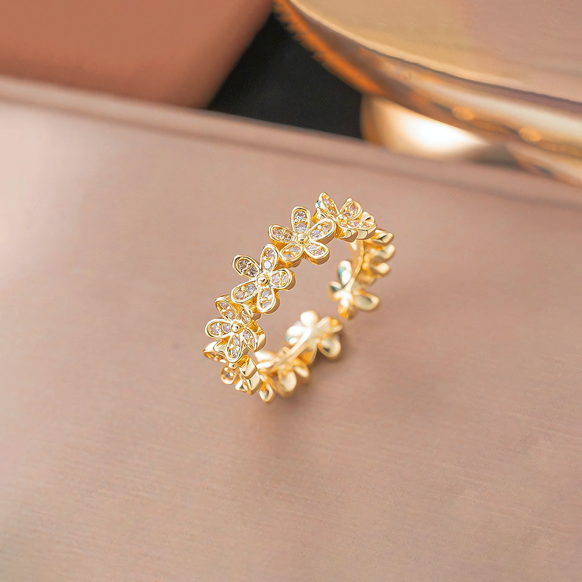 Fleur gold plated anti-tarnish floral ring standing on a smooth blush pink surface