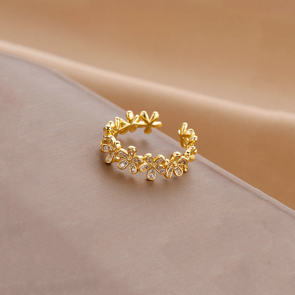 Fleur anti-tarnish gold floral open band ring resting on a folded taupe display surface
