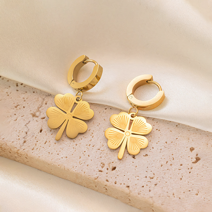 Flat lay of Ivy gold anti-tarnish clover earrings on textured beige stone