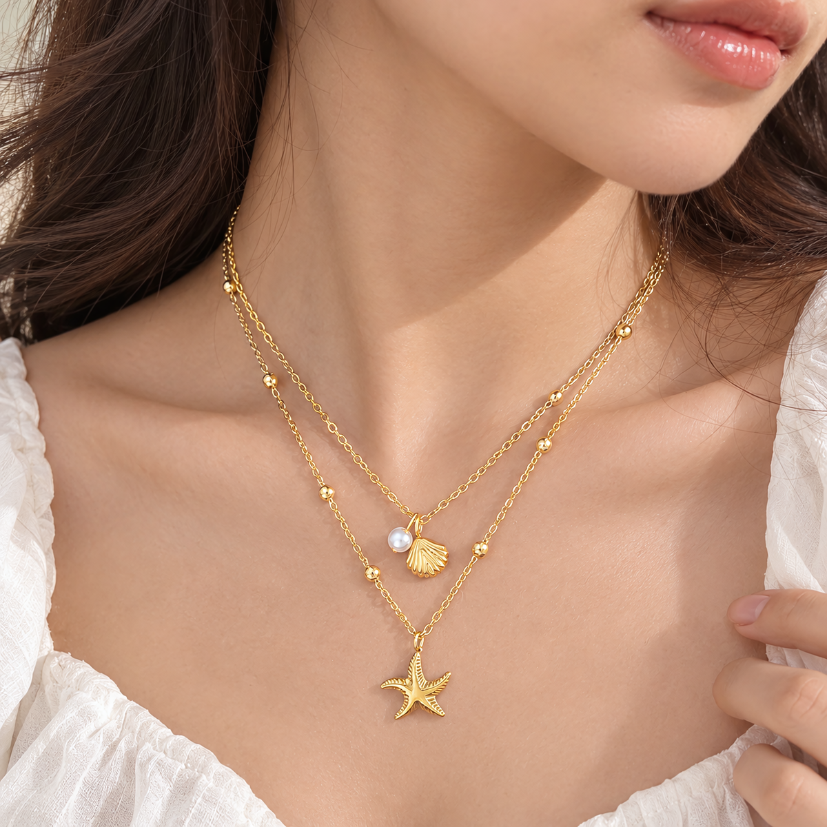 Model wearing the Marina anti-tarnish gold layered starfish and seashell necklace on the collarbone