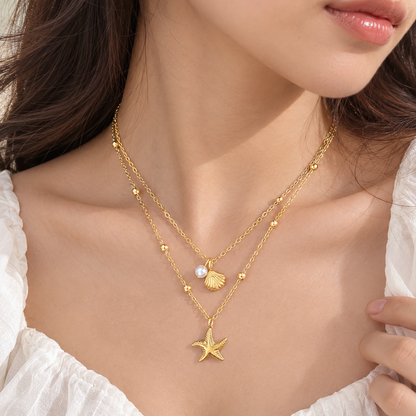 Model wearing the Marina anti-tarnish gold layered starfish and seashell necklace on the collarbone
