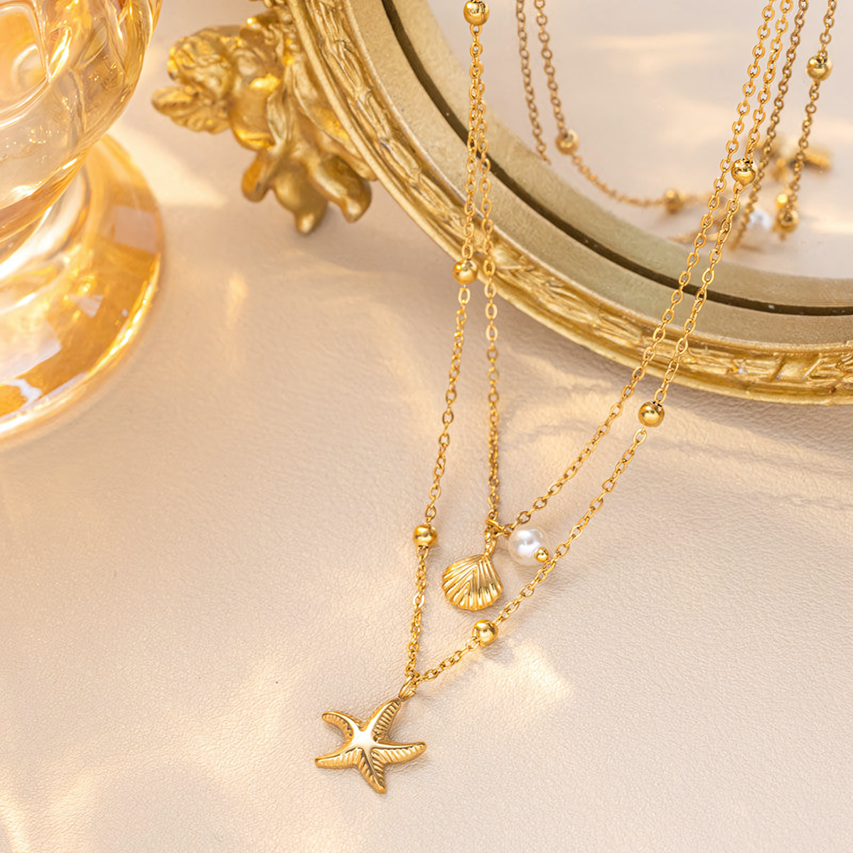 Marina gold anti-tarnish layered necklace with ocean charms hanging in front of a vintage gold mirror