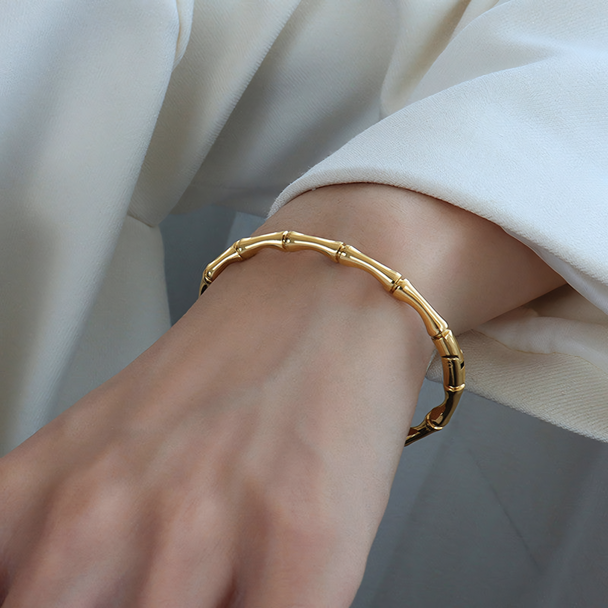 Model wearing the Mila anti-tarnish gold bamboo bracelet on wrist with a white blazer