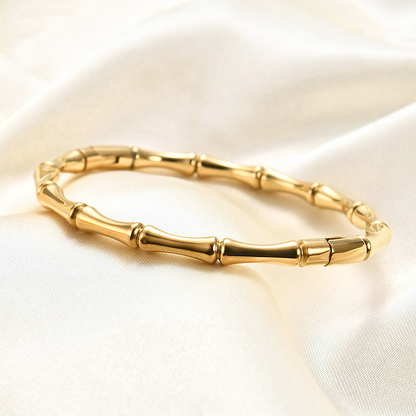 Mila anti-tarnish gold bamboo bracelet resting on white silk showing the seamless hinge clasp