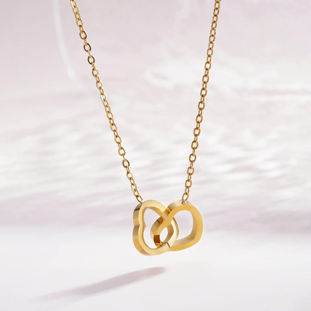 Close up of the Nova anti-tarnish gold double interlocking heart pendant and cable chain