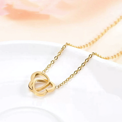 Nova gold plated anti-tarnish interlocking hearts necklace flat lay on white ceramic plate