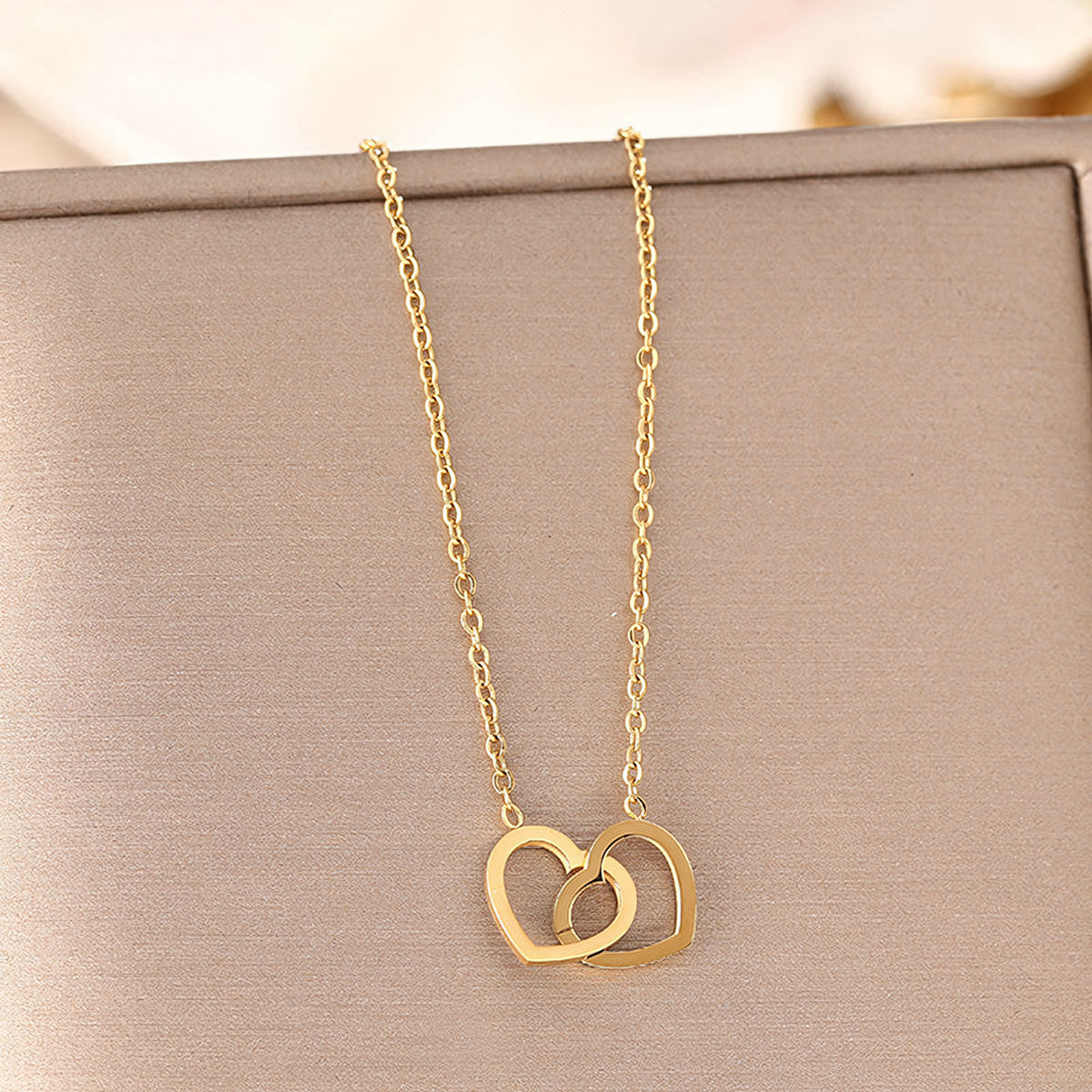 Nova gold plated anti-tarnish interlocking hearts necklace resting inside a premium jewelry gift box